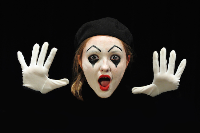 Image of a mime staring at camera, mouth agape and hands open with palms facing camera